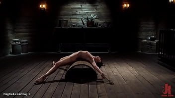 Bound to wooden pony in squat position with legs and hands spreaded wide brunette slave Kristen Scott gets clamped then takes back arch bondage over half barrel by master The Pope